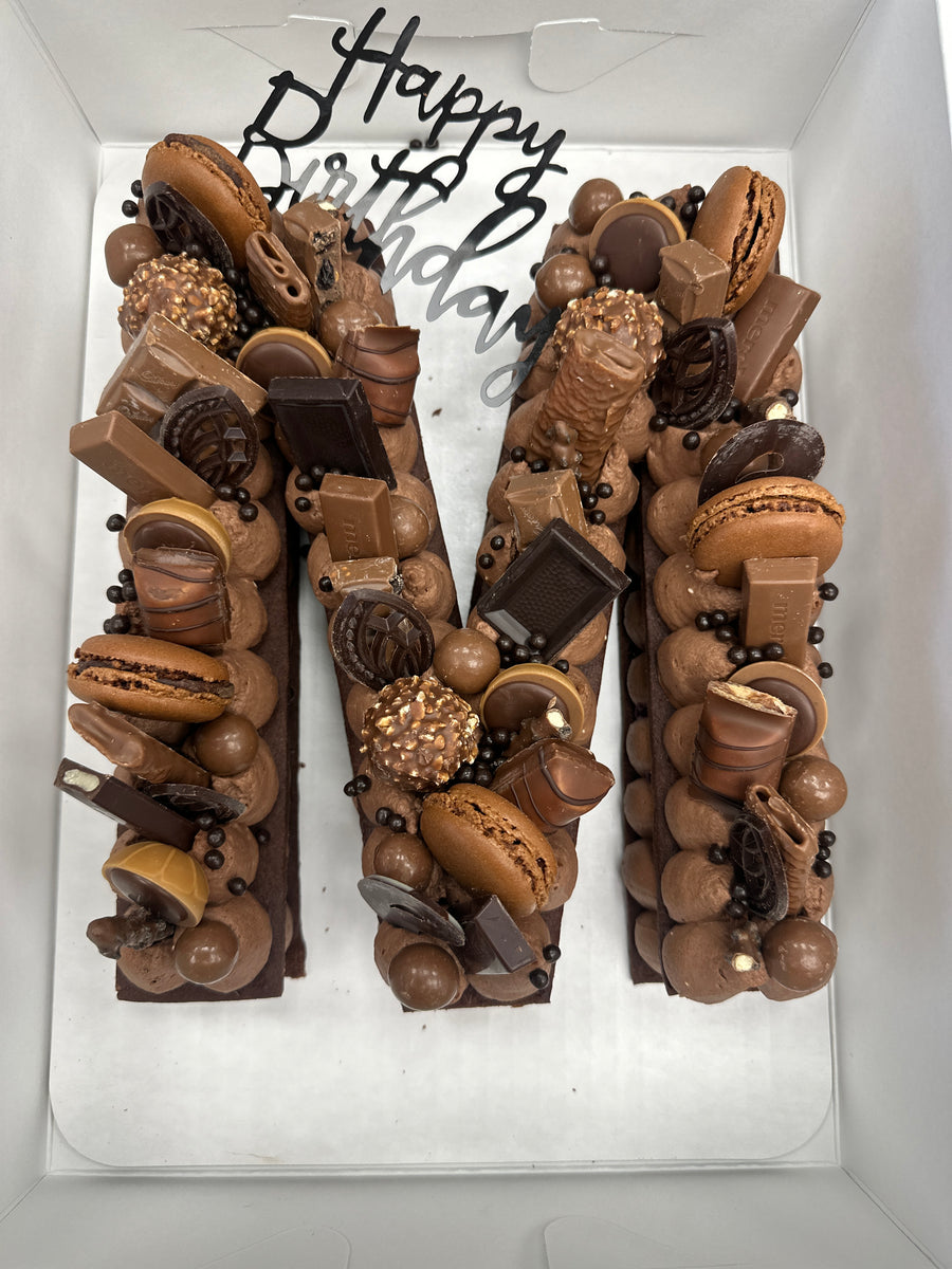 Chocolate letter M Dream Tart topped with macarons and chocolates